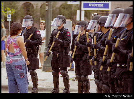 A protestor confronts a squad of Austin Police Officers in riot gear  during the Fortune 500 meeting protest.