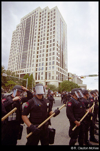 Austin Police Officers in riot gear watch protesters and press during the Fortune 500 meeting protest.